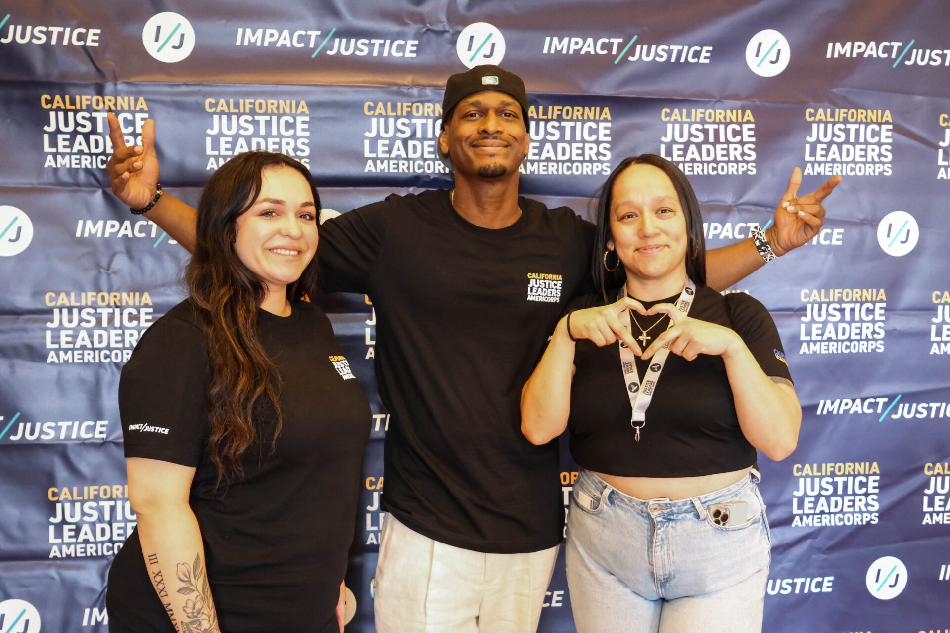 Three young people smiling against a backdrop featuring the California Justice Leaders and Impact Justice logos.
